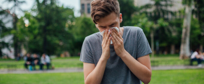 A person blowing their nose in a city centre park