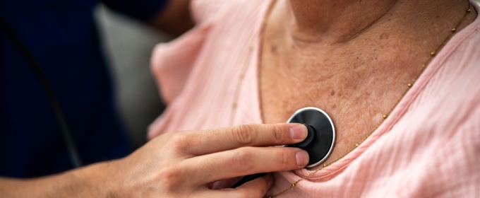 A medical practitioner listening to a woman's chest with a stethoscope